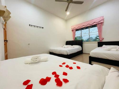 een kamer met 2 bedden en rode rozenblaadjes op de lakens bij GreenPine Kota Tinggi Homestay in Kota Tinggi