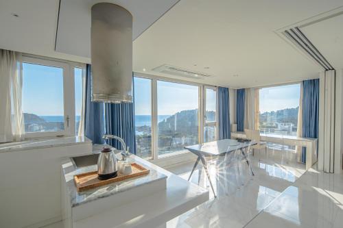 a kitchen with a sink and a counter with windows at From H Oceanpalace Hotel Jeju in Seogwipo
