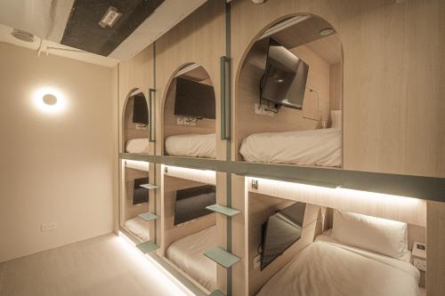 a room with three bunk beds and two mirrors at Jyu Capsule Hotel in Singapore