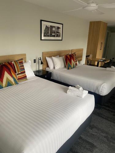 a hotel room with two beds and a table at AVENUE MOTEL APARTMENTS in Toowoomba