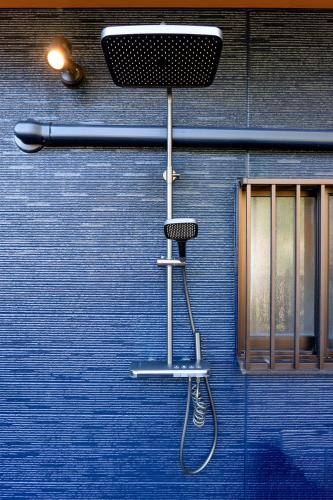 a shower in front of a blue wall with a shower head at SMART VILLA Hakone Sukumogawa Riverside in Hakone