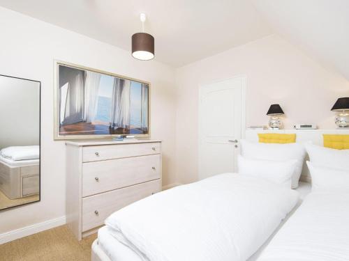 ein weißes Schlafzimmer mit 2 Betten und einem Spiegel in der Unterkunft Strandidyll in Kampen