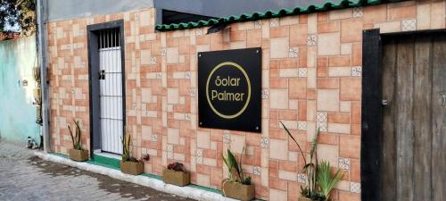 a sign on the side of a brick building with plants at Apartamentos SOLAR PALMER in Cabo Frio