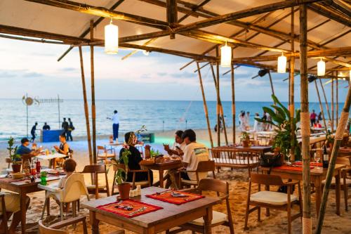 grupa ludzi siedzących przy stolikach na plaży w obiekcie Santhiya Phuket Natai Resort & Spa w mieście Natai Beach