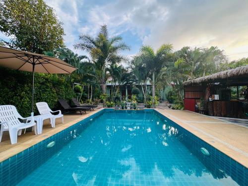 a swimming pool with two chairs and an umbrella at AJ Paradise Resort Aonang Krabi in Ao Nang Beach