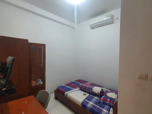 a small room with a bed and a table and a desk at OYO 93444 Damia Homestay Syariah in Surabaya