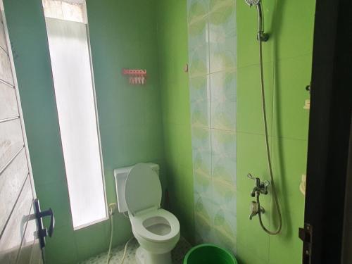 a green bathroom with a toilet and a shower at OYO 93444 Damia Homestay Syariah in Surabaya