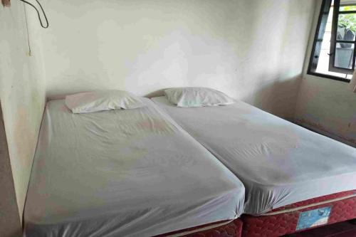a bed in a room with two pillows on it at SPOT ON 93436 Penginapan Mekar Sari in Kuripan