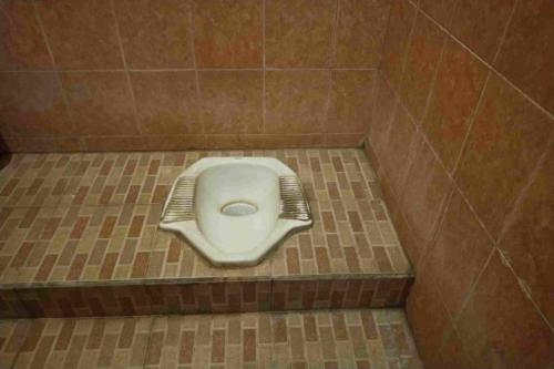 a bathroom with a toilet in a tiled floor at SPOT ON 93436 Penginapan Mekar Sari in Kuripan