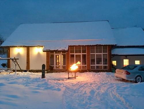a house with a fire in front of it in the snow at Holiday home Usadba Novoselitsa in Novoselitsa