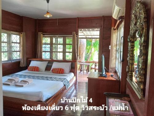 a bedroom with a bed and a tv and windows at เรือนแฝด Brook view in Pai