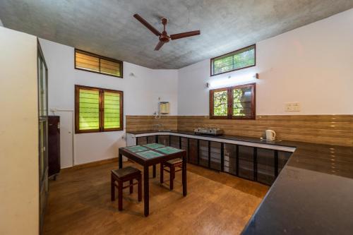 a kitchen with a table and a ceiling fan at Aurovidya Retreat in Kottakupam
