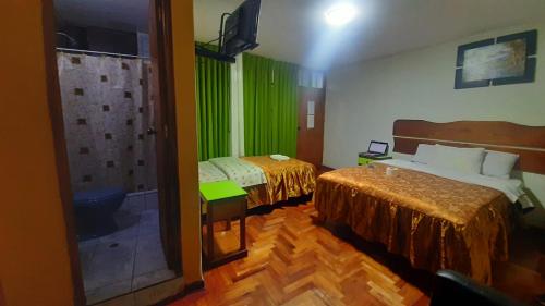 a room with two beds and a bathroom with green curtains at Sierra Verde - Muy Céntrico Hs in Huancayo