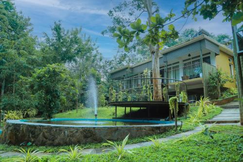 a house with a fountain in the yard at Kuruva Island Resort And Spa - By KABINI BREEZE, Wayanad in Mananthavady