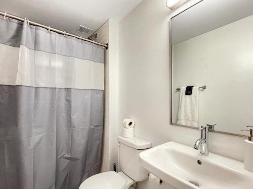 a bathroom with a toilet and a sink and a mirror at Quiet Studio On Grand - Downtown Dsm! in Des Moines
