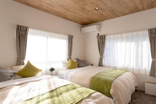 a bedroom with two beds and a window at SMART VILLA Hakone Sukumogawa Riverside in Hakone