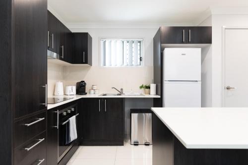 a kitchen with black cabinets and a white refrigerator at New Listing! Air-Con and Well Presented! in Brisbane