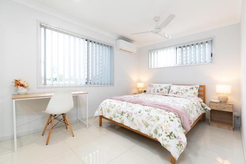 a bedroom with a bed and a desk and two windows at New Listing! Air-Con and Well Presented! in Brisbane