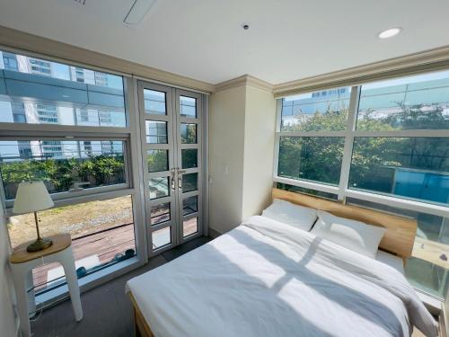 a bedroom with a large bed and large windows at Busan Centurn Victoria hotel in Busan