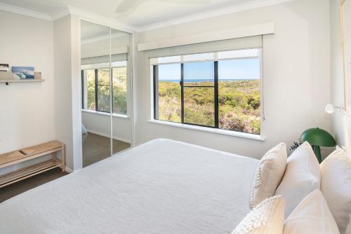 a white bedroom with a large bed and two windows at Panorama at Margarets Beach in Gnarabup