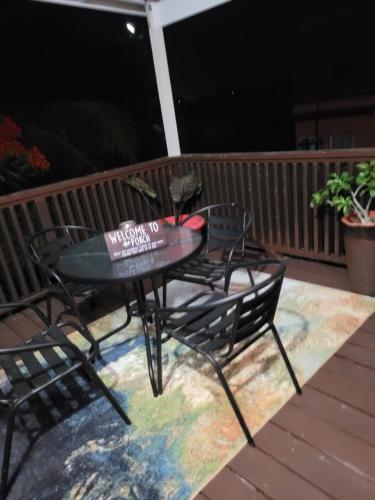 a patio table and chairs on a deck at night at Silverbuttons Apartments & Eats in Dickenson Bay