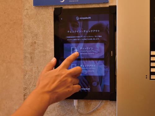 a person is pointing to a sign on a pay phone at Condominium L's INN in Naha