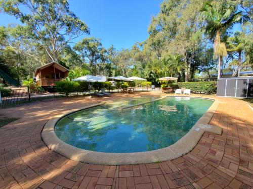 a swimming pool in a yard with a brick patio at Captain Cook Holiday Village 1770 in Seventeen Seventy