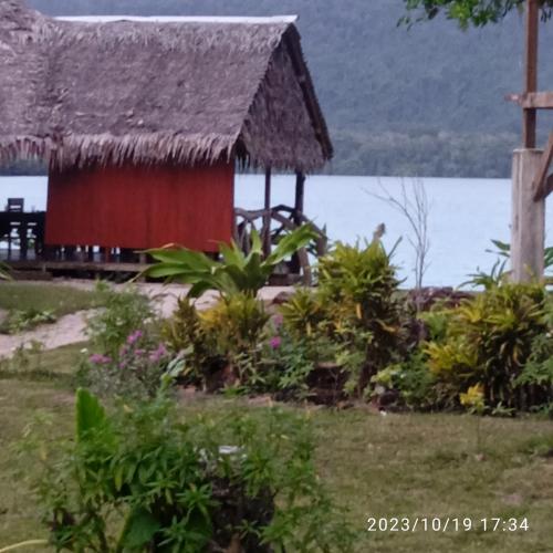 a house with a thatched roof next to the water at Serenity Bungalows in Port-Olry