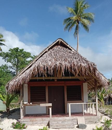 Cabaña con techo de paja y palmera en Serenity Bungalows, en Port-Olry