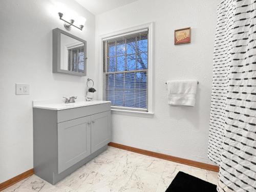 een witte badkamer met een wastafel en een raam bij 3bed Cozy House In Quiet Neighborhood in Des Moines