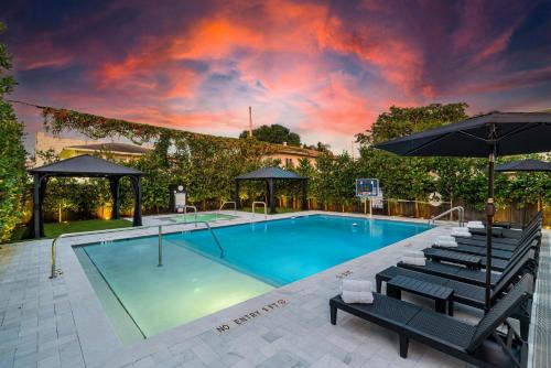 a pool with chairs and umbrellas next to a building at Lux Retreat By Renzzi in Miami