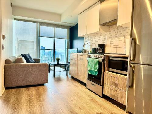 a kitchen with a couch and a stove top oven at Cozy 2 Bedroom by Eaton Centre Mall in Toronto