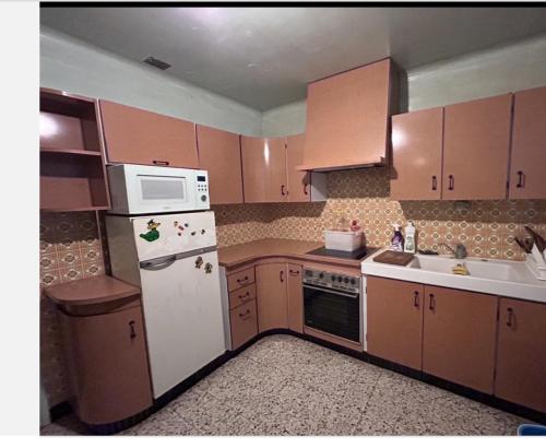 La cuisine est équipée de placards bruns et d'un réfrigérateur blanc. dans l'établissement 住在巴黎, à Bondy