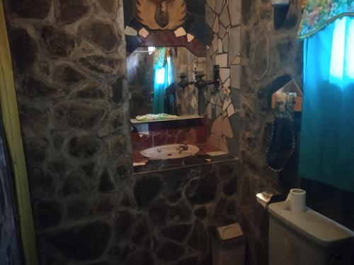 Baño de piedra con lavabo y espejo en Yoschi's Hotel Bromo, en Ngadisari