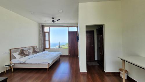 a bedroom with a bed and a large window at Salig Hotel in Dharamshala