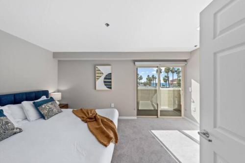 a white bedroom with a white bed and a window at Exquisite Ocean View Duplex Rooftop Santa Monica in Los Angeles