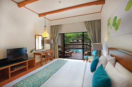 a bedroom with a bed and a television and a living room at Woodlands Hotel and Resort Pattaya in Pattaya North
