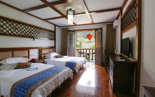 a bedroom with two beds and a television and a balcony at Mountainside in Zhangjiajie