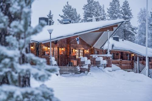 a log cabin in the snow with snow covered trees at Hotel Kuusamon Portti in Kuusamo