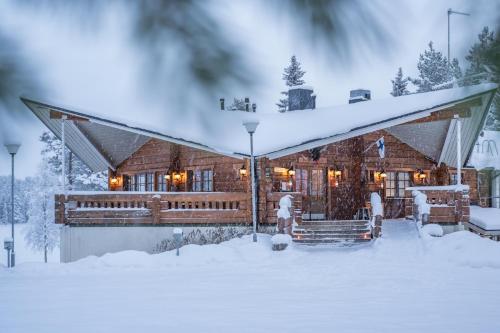 una cabaña de madera en la nieve cubierta de nieve en Hotel Kuusamon Portti, en Kuusamo