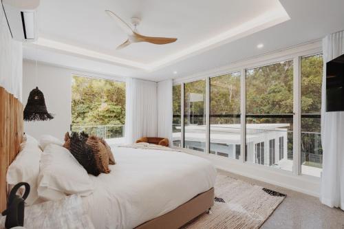 a bedroom with a large bed and a balcony at Belle Escapes Villa by the C in Palm Cove