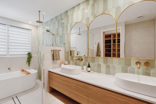 a bathroom with two sinks and a large mirror at Belle Escapes Villa by the C in Palm Cove