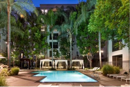a swimming pool in front of a building with palm trees at Blue Topaz Retreat - Spacious 3BR Gorgeous City views in Los Angeles