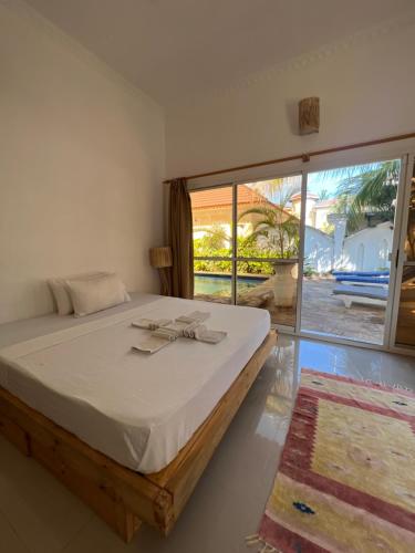 a bedroom with a bed and a large window at UKAYA VILLA in Paje