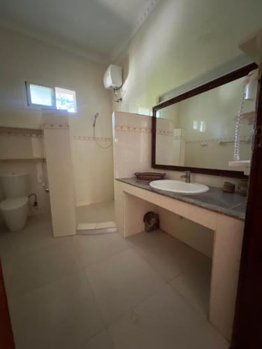 La salle de bains est pourvue d'un lavabo et d'un miroir. dans l'établissement UKAYA VILLA, à Paje