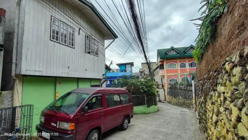 um pequeno carro vermelho estacionado ao lado de um edifício em Kochimoto Homestay em Baguio