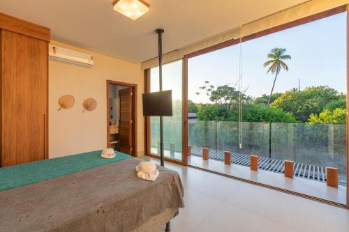a bedroom with a large window and a bed with a television at Casa Ofir - Alto Padrão in Praia do Forte
