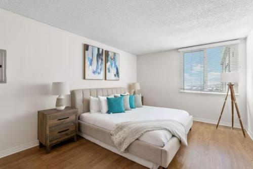 a white bedroom with a bed with blue pillows at Stunning Ocean View 1BR Venice Beach Marina DelRey in Los Angeles