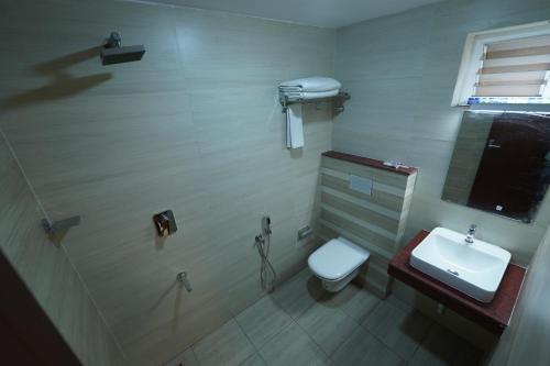 a bathroom with a toilet and a sink at Hotel Newline Orchid in Guruvāyūr