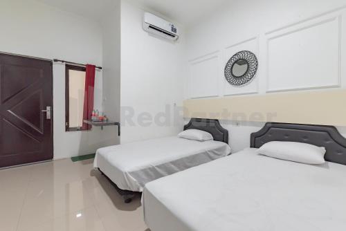 2 Betten in einem weißen Zimmer mit Spiegel in der Unterkunft JM Guest House Lamaran RedPartner in Karawang